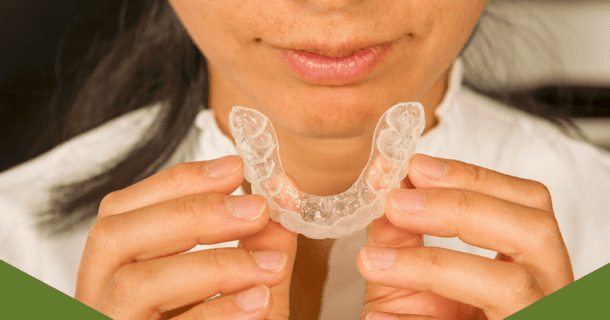 Close-up of woman's hands holding an Invisalign aligner.